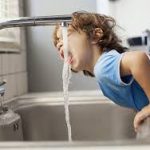 little child drinking water from faucet